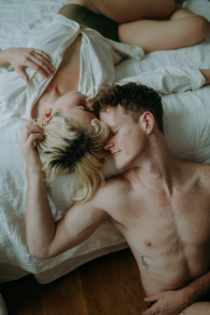 Couple cuddling in bed during intimate couple session NYC morning light natural unposed photography