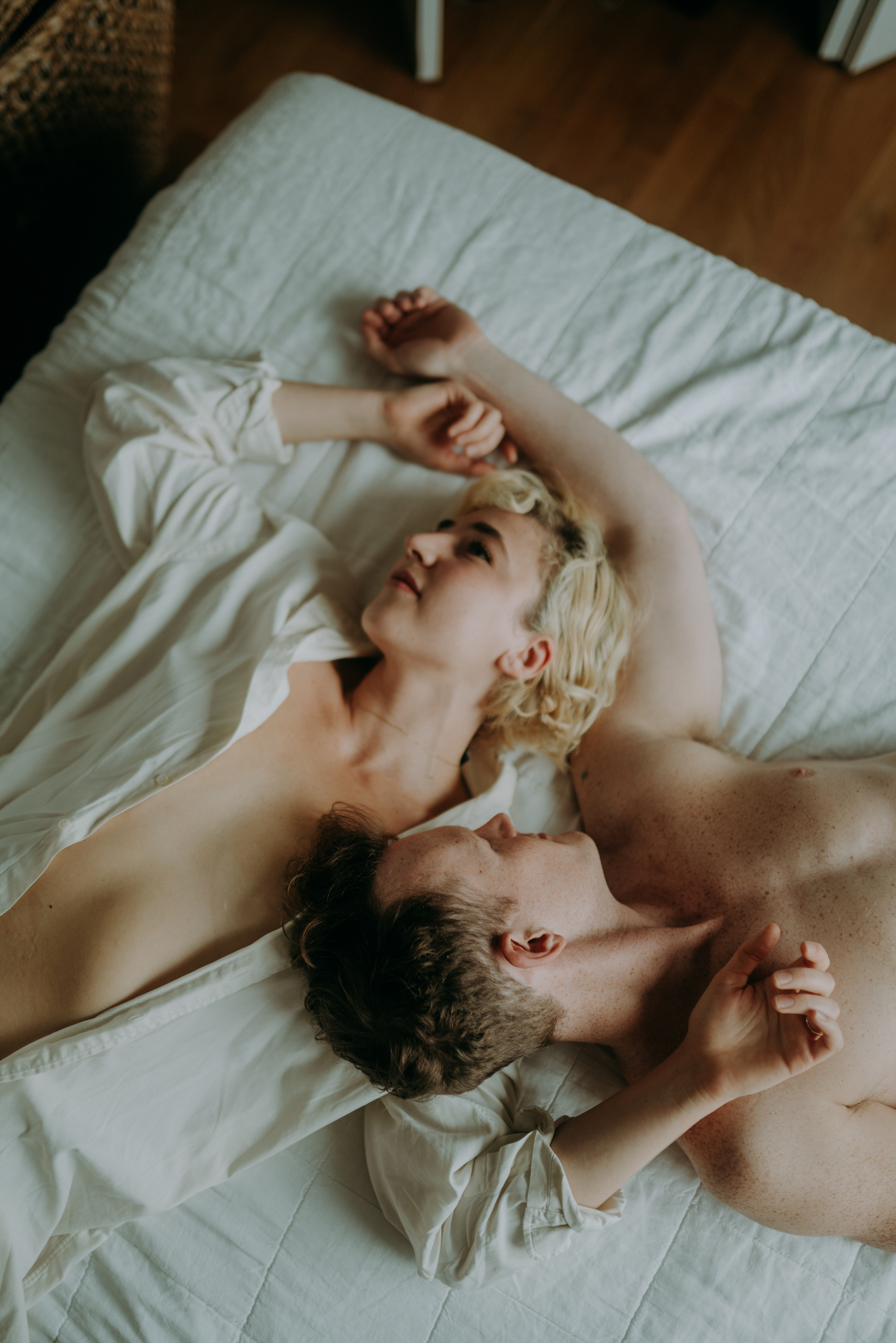 Couple cuddling in bed during intimate couple session NYC morning light natural unposed photography