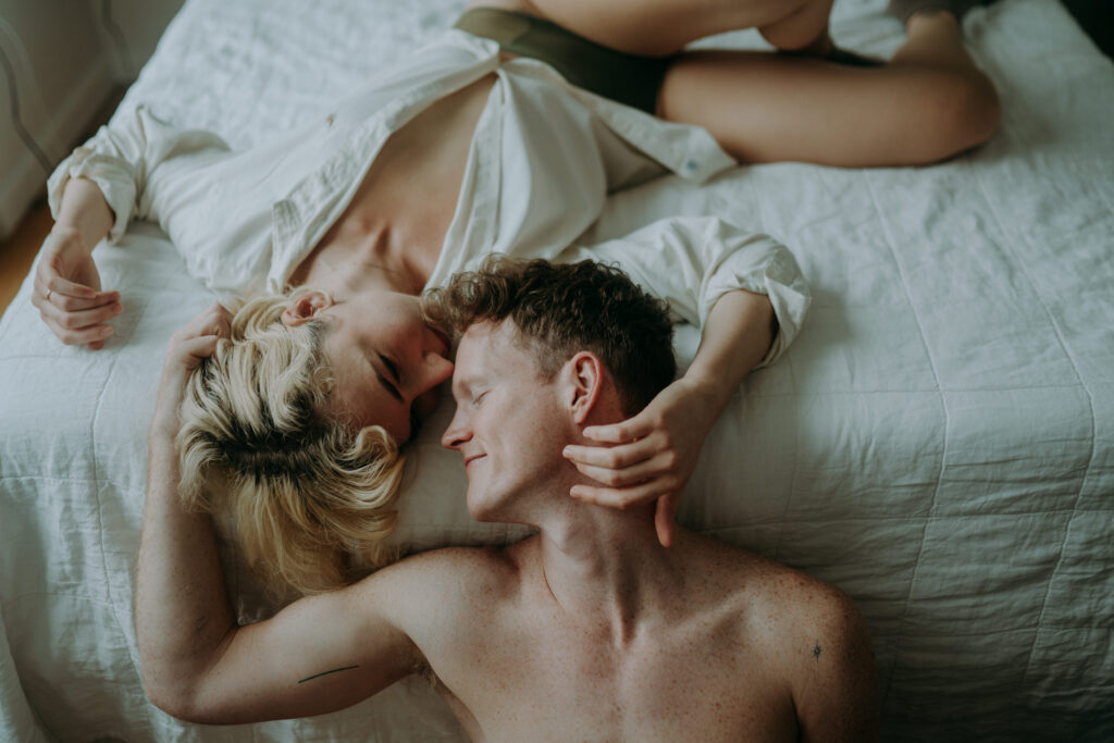 Couple cuddling in bed during intimate couple session NYC morning light natural unposed photography